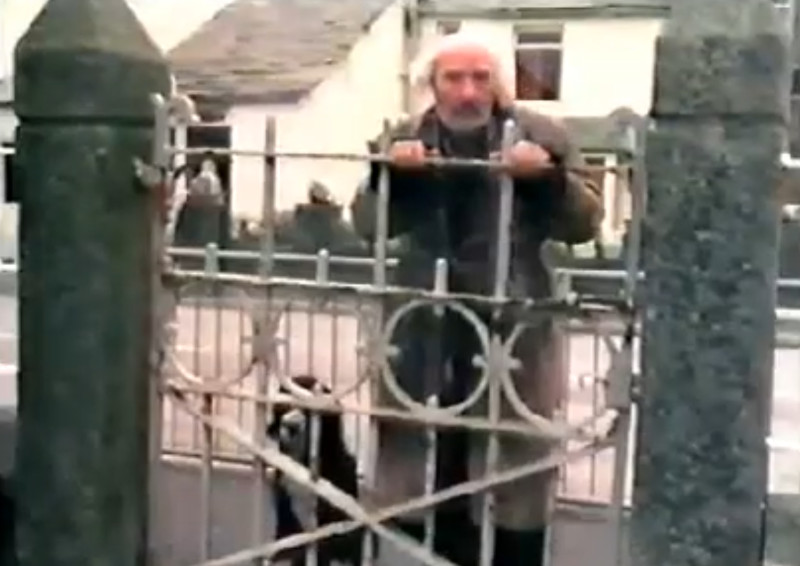 Tarry-Dan peering over the school railings Peering over the railings (Paul Curran as Tarry-Dan)